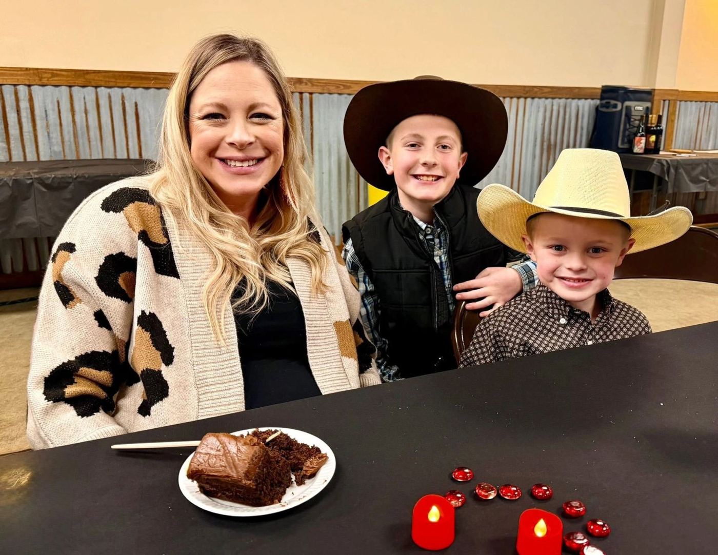 A mother and two young boys in cowboy hats at dinner